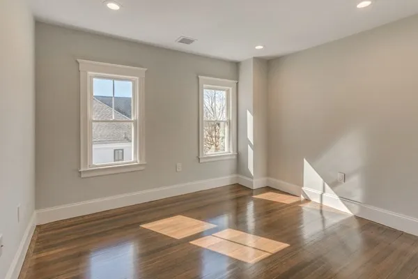 a view of an empty room with wooden floor and a window