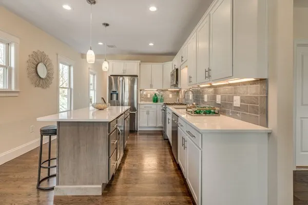 a kitchen with kitchen island granite countertop a sink a counter top space and stainless steel appliances