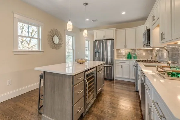 a kitchen with stainless steel appliances a sink a stove a refrigerator cabinets and a window