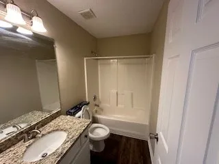 a bathroom with a granite countertop sink toilet and shower