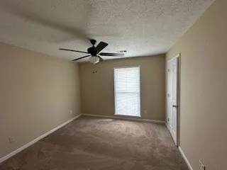 an empty room with windows and fan