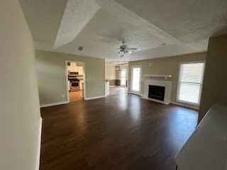 an empty room with wooden floor fireplace and windows