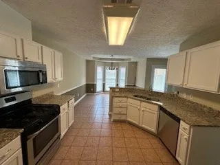 a large kitchen with granite countertop a stove sink and cabinets