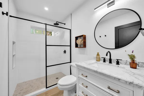 a bathroom with a granite countertop sink toilet mirror and vanity