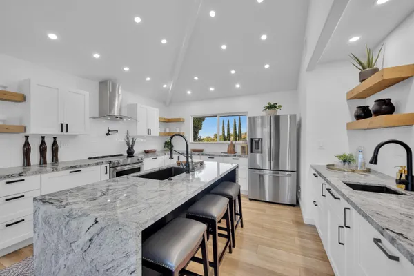 a kitchen with stainless steel appliances granite countertop sink stove and refrigerator
