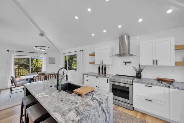 a open kitchen with granite countertop a stove a sink a dining table and chairs