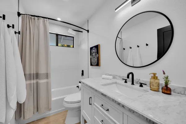 a bathroom with a toilet a sink a mirror and shower