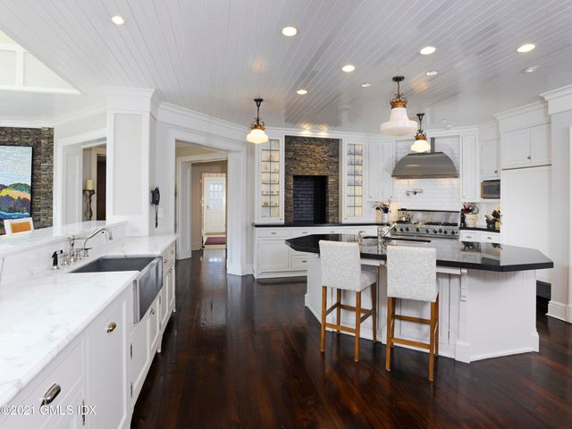 a open kitchen with stainless steel appliances granite countertop a stove top oven a sink dishwasher and white cabinets with wooden floor