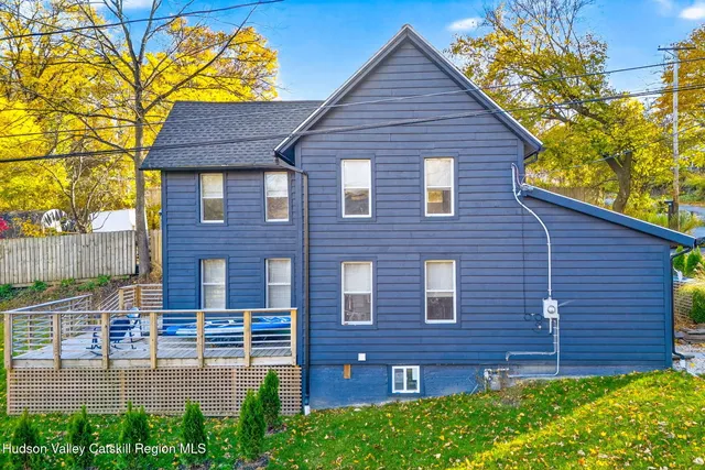 a brick house with a small yard plants and a large tree