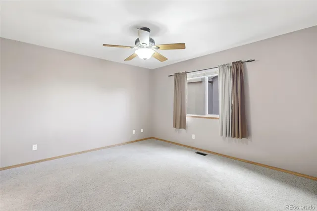 an empty room with windows and fan