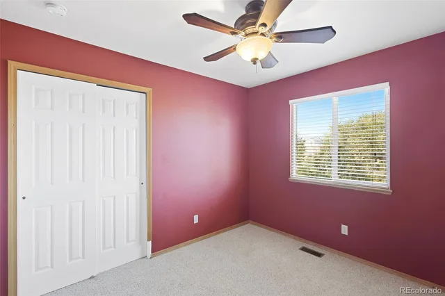 an empty room with a window and a fan