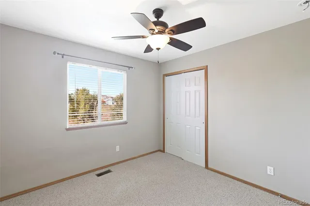 an empty room with ceiling fan and window