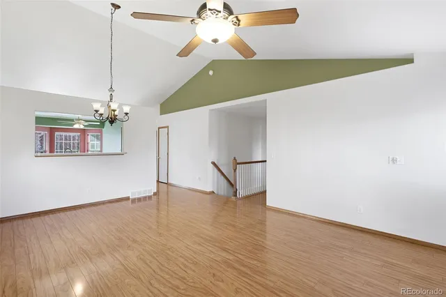 a view of a room with wooden floor ceiling fan and windows