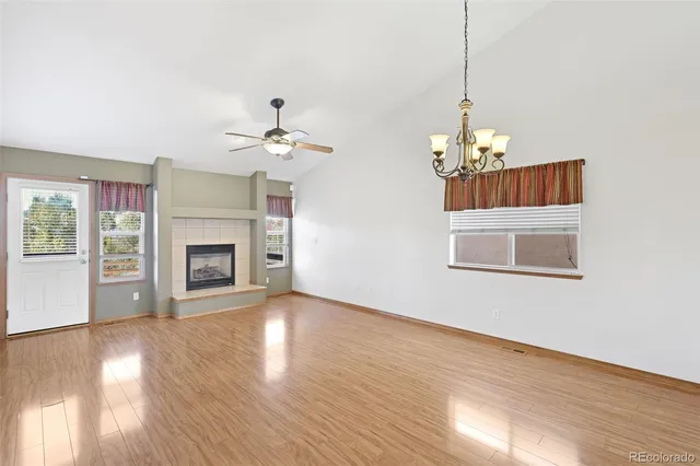 a view of an empty room with a chandelier fan and fire place