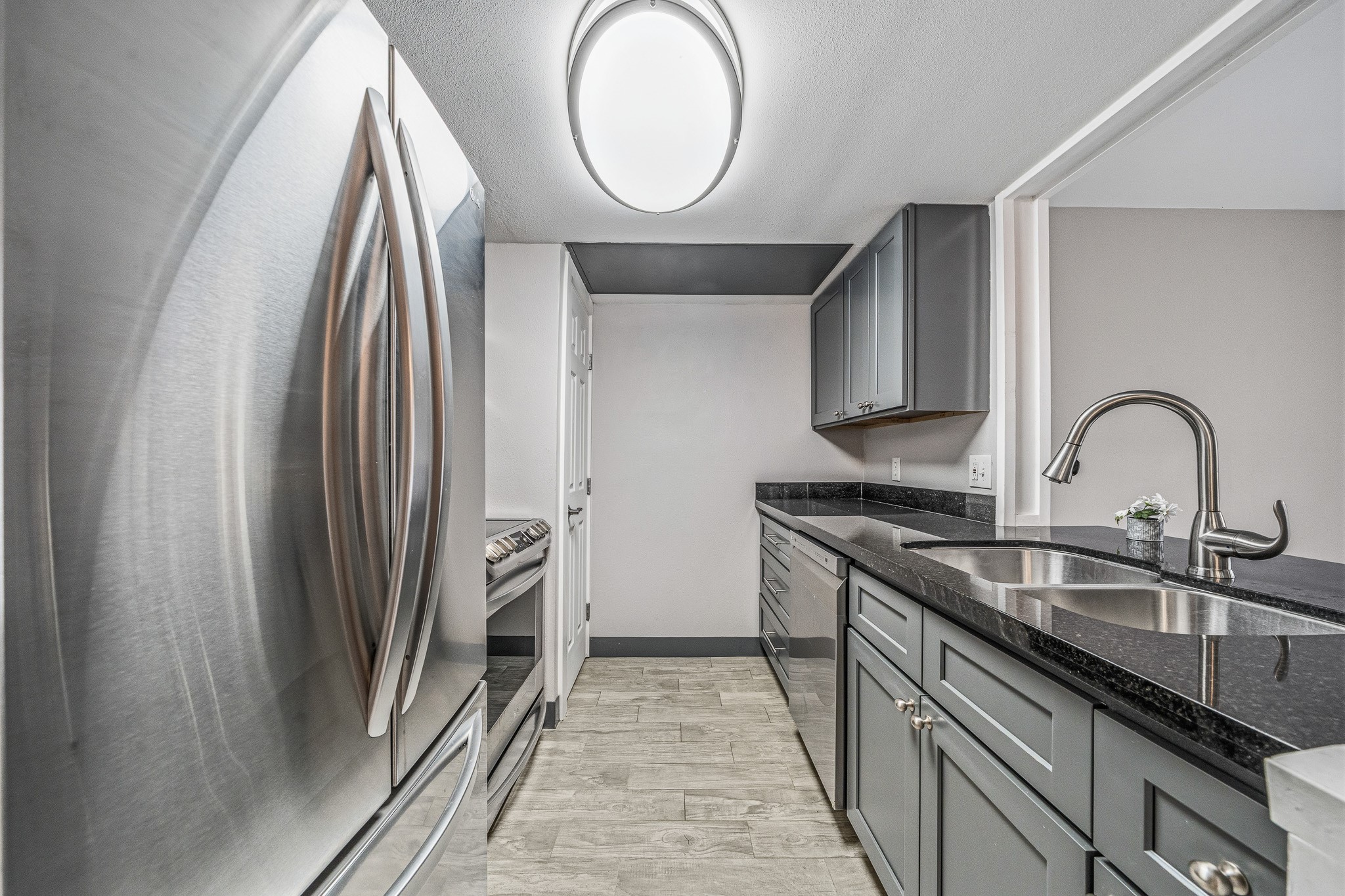 830 Threadneedle Street, Unit 240 Houston, TX 77079 - Photo 9 of 33 Modern kitchen with sleek stainless steel appliances, gray cabinetry, and black granite countertops. Features a double sink and ample storage, complemented by stylish lighting and neutral-toned flooring.