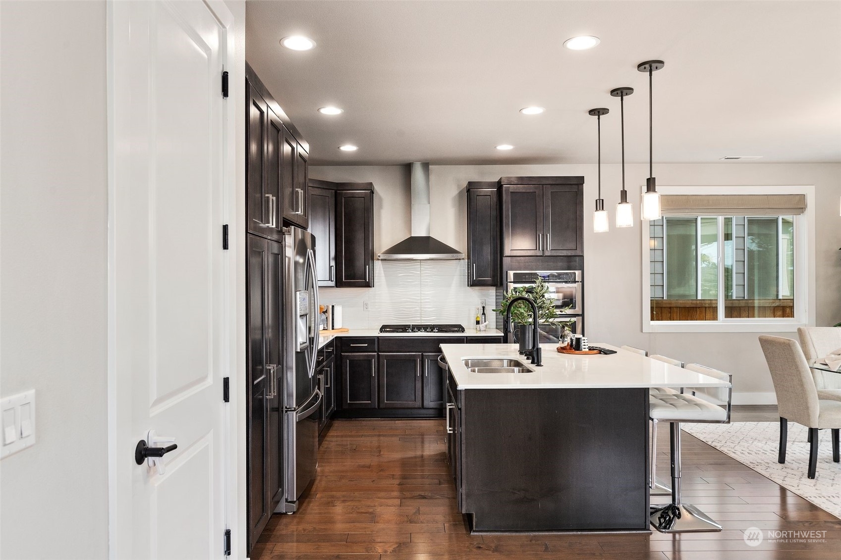 22322 43rd Drive Southeast Bothell, WA 98021 - Photo 13 of 40 a kitchen with stainless steel appliances granite countertop a refrigerator a sink dishwasher a stove and a dining table with wooden floor