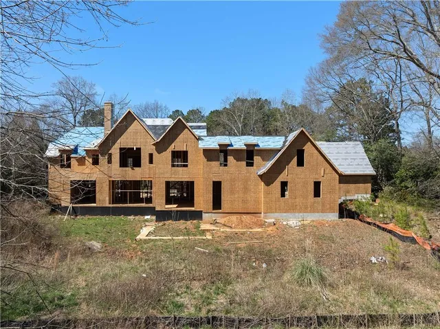 a view of a white house next to a yard with large trees