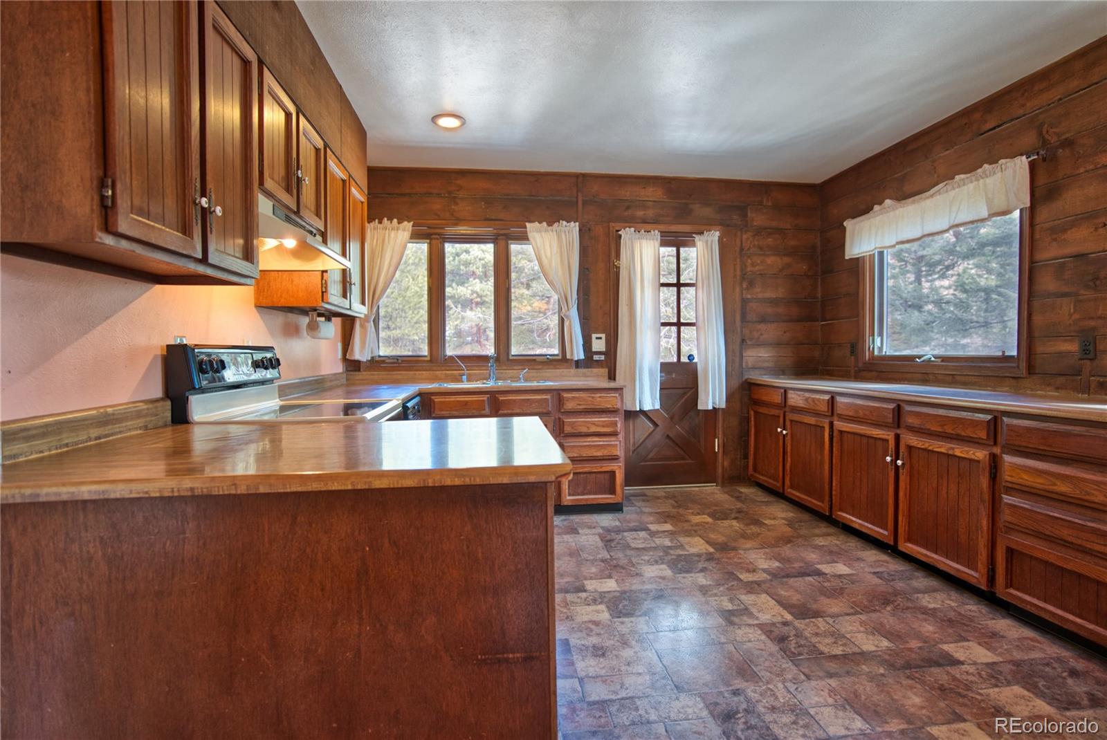 601 Pika Road Boulder, CO 80302 - Photo 9 of 30 a large kitchen with stainless steel appliances a large counter top a stove a chimney a sink and dishwasher