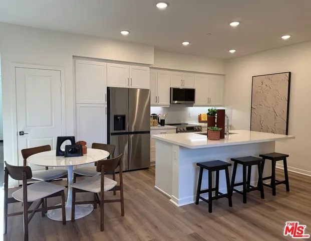 a kitchen with a dining table chairs refrigerator and cabinets