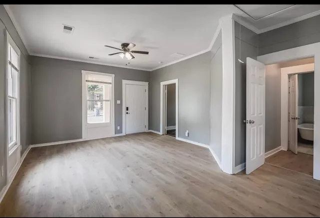 an empty room with wooden floor ceiling fan and windows