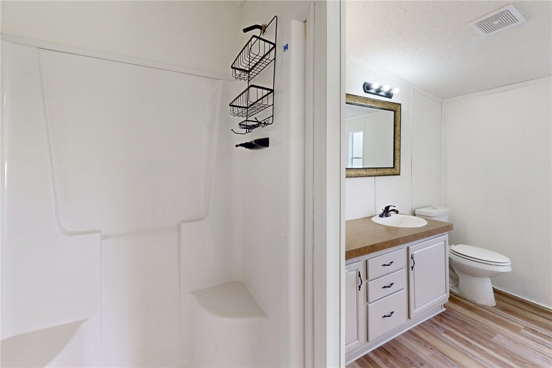 11459 Winstead Lane Calvert, TX 77837 - Photo 23 of 37 a bathroom with a granite countertop sink a toilet and a shower