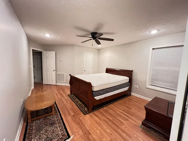 a spacious bedroom with a bed and wooden floor