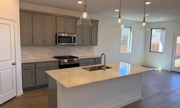 a kitchen with stainless steel appliances granite countertop a sink a stove a refrigerator and cabinets with wooden floor