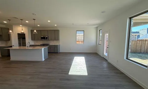 a open kitchen with stainless steel appliances granite countertop a refrigerator a sink dishwasher and a oven with wooden floors