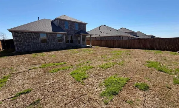 a front view of a house with a yard and wooden fence