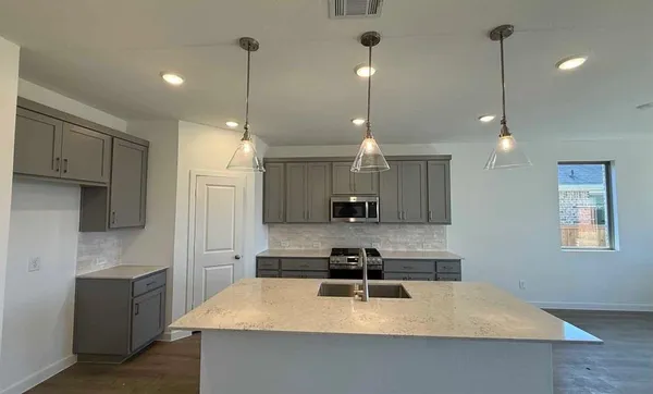 a view of an empty room with wooden floor and windows
