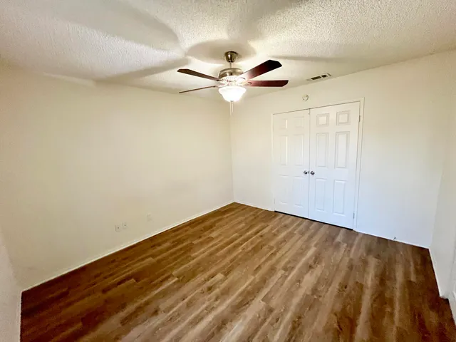 a view of empty room with wooden floor and fan