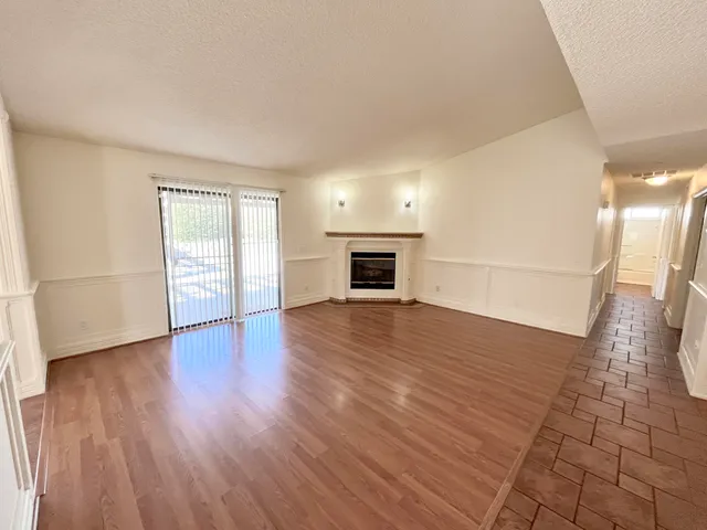an empty room with wooden floor and fireplace