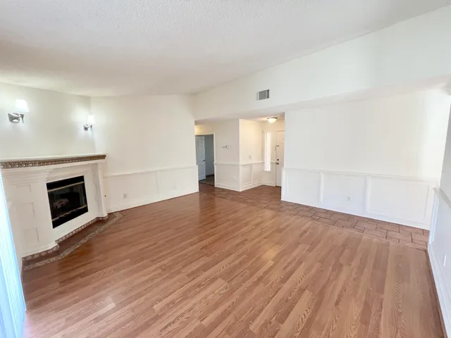 a view of empty room with wooden floor and fireplace