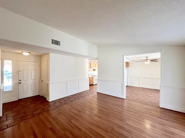 an empty room with wooden floor & windows and bathroom