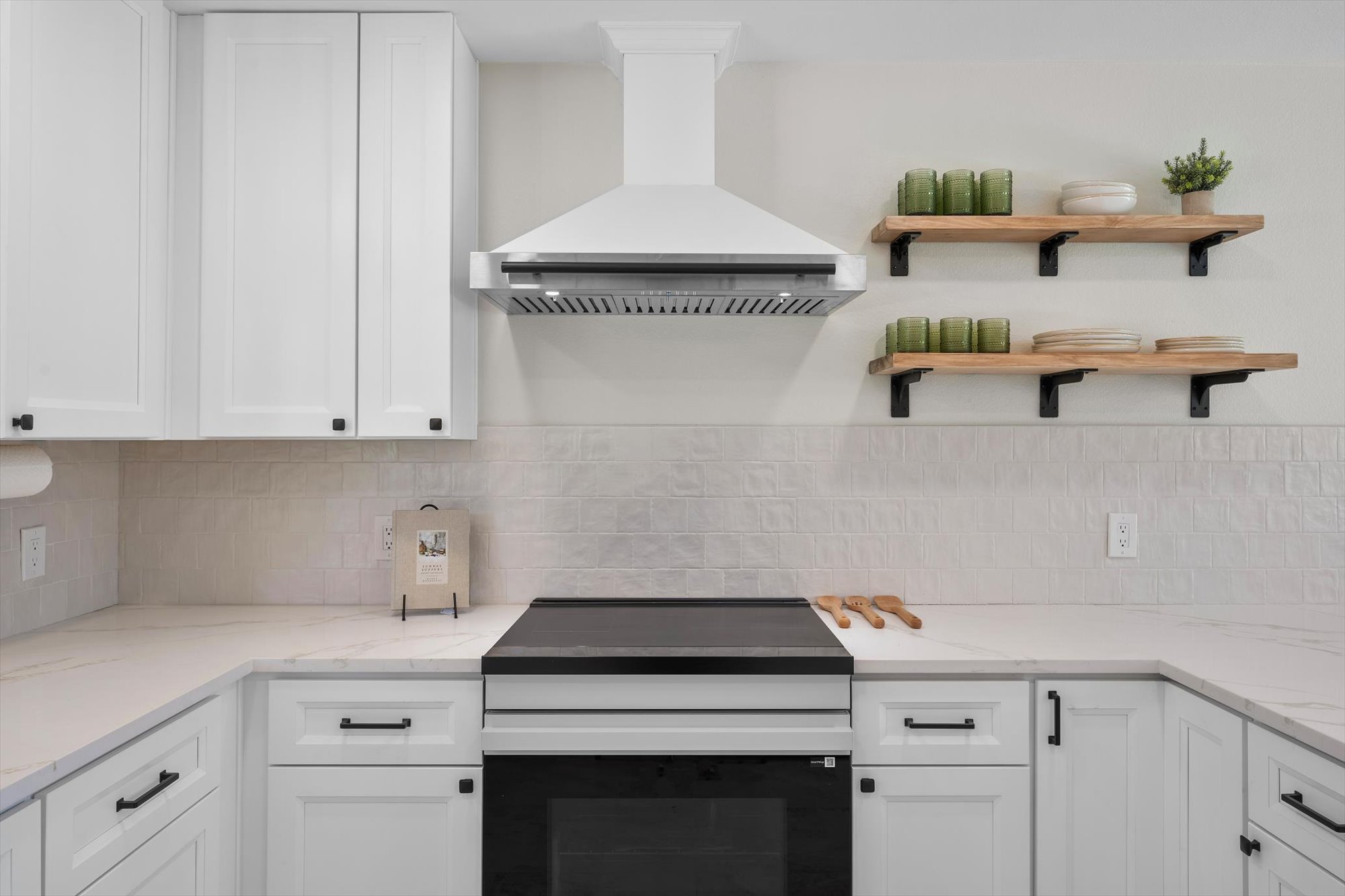 109 Woodland Road Georgetown, TX 78628 - Photo 17 of 40 Modern kitchen featuring sleek white cabinetry, a stylish range hood, and open shelving for a clean aesthetic.