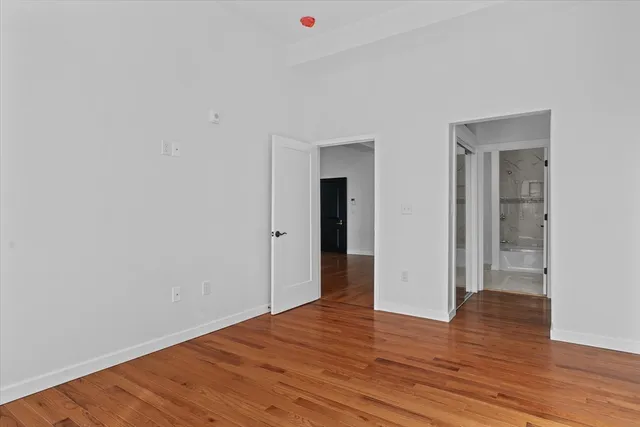 a view of an empty room with wooden floor and closet