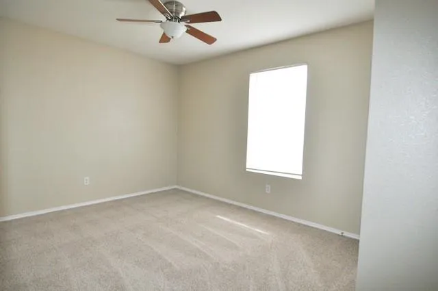 an empty room with a window and a fan