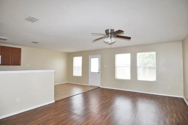 a view of empty room with wooden floor and fan