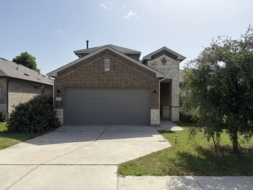 10708 Gonzales Ranger Pass Austin, TX 78754 - Photo 1 of 40 A welcoming facade with a blend of brick and stone accents, plus an attached garage.