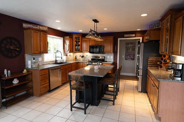 a kitchen with kitchen island granite countertop a sink appliances and cabinets
