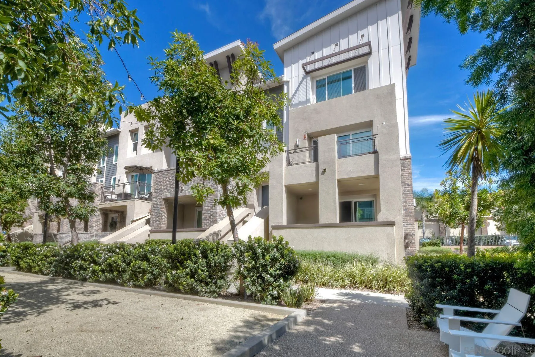 6058 Colt Place, Unit 101 Carlsbad, CA 92009 - Photo 1 of 42 a front view of a multi story residential apartment building with yard and parking