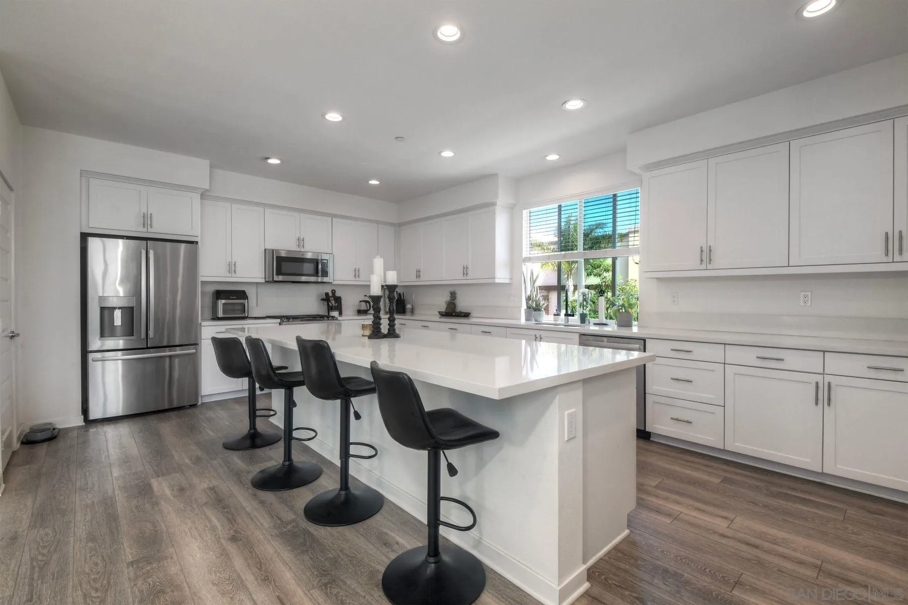 6058 Colt Place, Unit 101 Carlsbad, CA 92009 - Photo 5 of 42 a kitchen with stainless steel appliances granite countertop a stove a sink a refrigerator and white cabinets with wooden floor