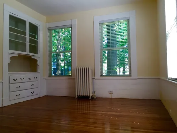 a view of an empty room with a window and cabinet