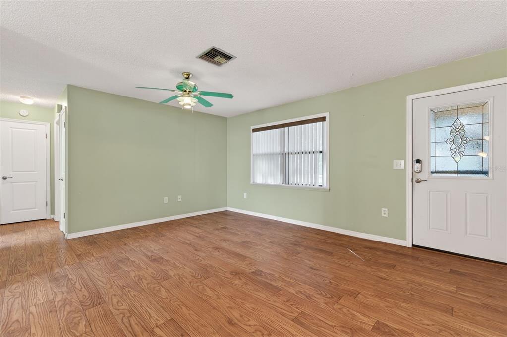 7157 Landmark Drive Spring Hill, FL 34606 - Photo 11 of 57 an empty room with wooden floor chandelier fan and windows