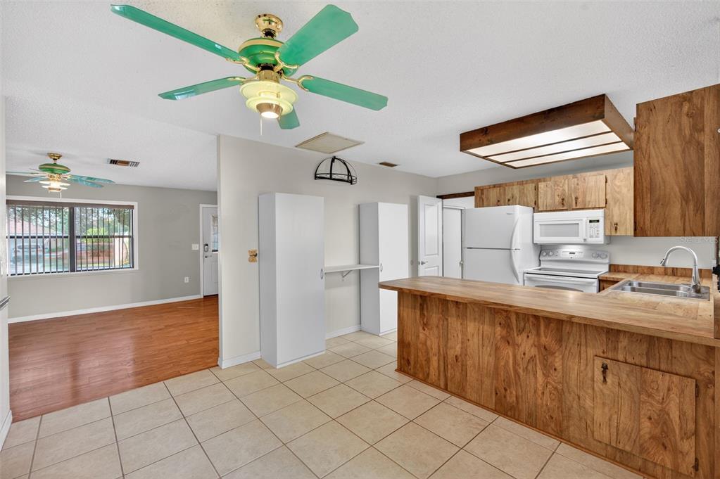 7157 Landmark Drive Spring Hill, FL 34606 - Photo 13 of 57 a kitchen with stainless steel appliances granite countertop a refrigerator a sink dishwasher and white cabinets with wooden floor