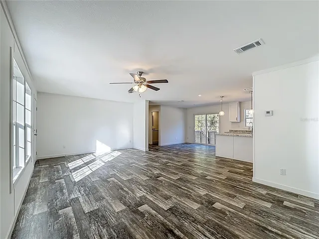 a view of an empty room with window and wooden floor