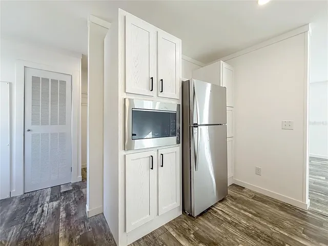 a view of kitchen with refrigerator cabinets and wooden floor