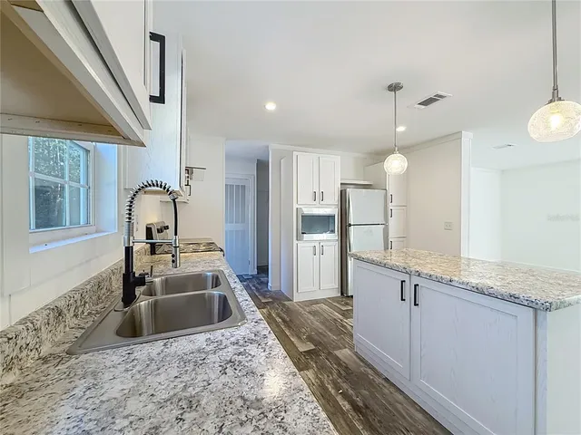 a large kitchen with granite countertop a sink stainless steel appliances and cabinets