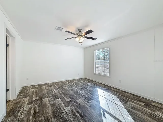 an empty room with wooden floor and ceiling fan