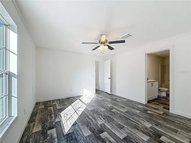 a view of an empty room and chandelier fan